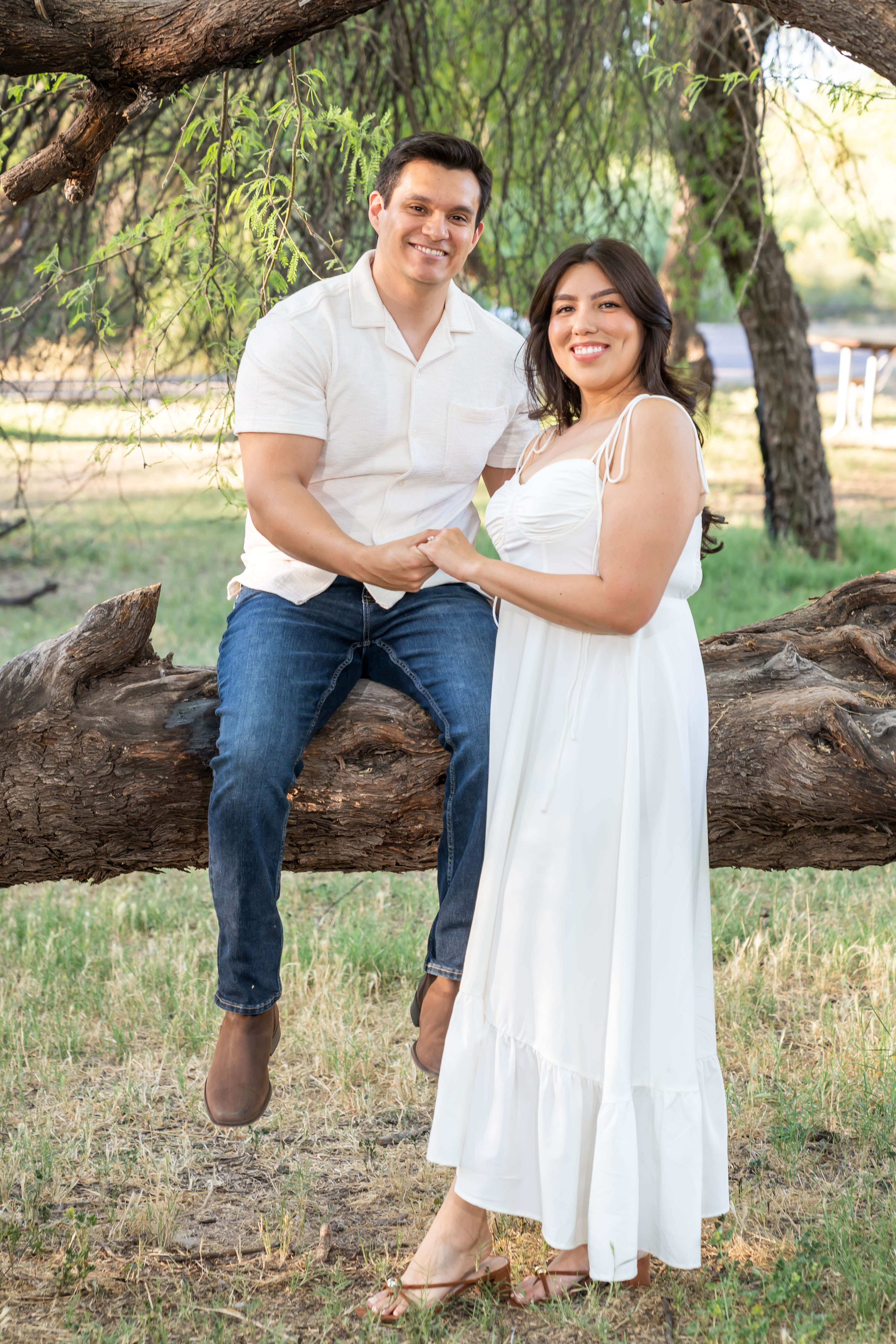 La pareja abrazada sonriendo en una toma horizontal elegante.